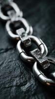 Close-up view of metallic chain links against a dark slate background showcasing intricate textures and reflections photo