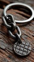 Close-up of a vintage keychain with a textured metal disc resting on weathered wooden surface photo
