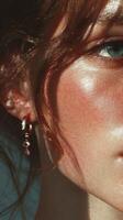 Close-up of a person showcasing shimmering skin and delicate earrings in natural light during a sunny day photo