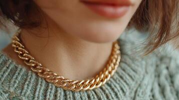 Close-up view of a person wearing a gold chain necklace while dressed in a cozy sweater in a well-lit indoor setting photo