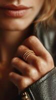 Close-up of a woman's hand adorned with stacked rings against a dark leather jacket background photo