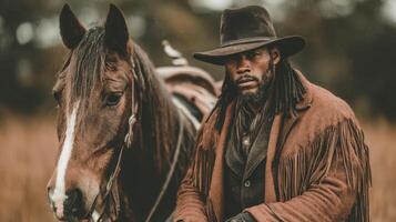 Man in cowboy attire poses with horse in a rustic setting during late afternoon light photo