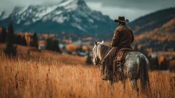 Cowboy on horseback gazes at mountain scenery during autumn in a tranquil valley photo