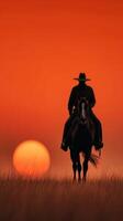 Silhouette of a cowboy riding a horse against a vibrant sunset in a wide open field photo