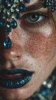 Close-up of a model showcasing intricate makeup with blue accents and stunning accessories during a fashion event at night photo