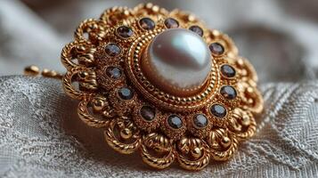 Intricately designed golden brooch with pearl centerpiece on elegant fabric backdrop photo