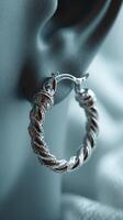Elegant silver hoop earring in close-up display on an ear, highlighting intricate design and craftsmanship in soft lighting photo