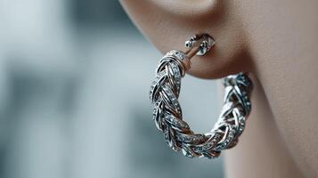 Elegant silver hoop earring with intricate design showcased on a model in a soft focus urban background photo