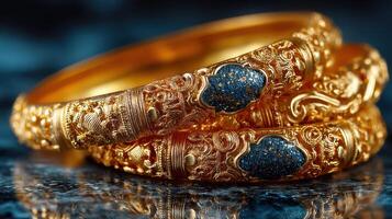 Elegant gold bangles with intricate designs and blue stone embellishments on a textured background photo