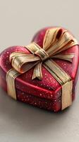 Heart-shaped gift box wrapped in gold ribbon sits on a smooth surface in soft natural light photo