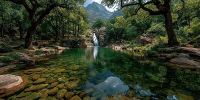 Scenic waterfall cascading into clear blue pool amidst lush greenery in a mountainous area during daylight photo