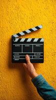 Clapperboard held against a vibrant yellow wall during film preparation for a creative project photo