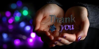 Hands hold a colorful thank you message against a blurred festive background photo