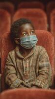 Young boy wearing a mask sitting quietly in a theater during a performance on a winter evening photo
