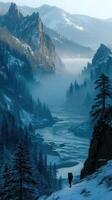 Hiker explores a misty valley surrounded by rugged mountains and snowy terrain at dawn photo