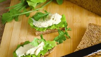 Slice of rye bread with cheese spread and greens on the table video