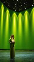 Performer stands confidently on stage in a vibrant green setting during an evening presentation at a modern theater venue photo
