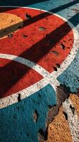 Colorful and worn basketball court surface showing vibrant patterns and weathering in the sunlight during afternoon hours photo
