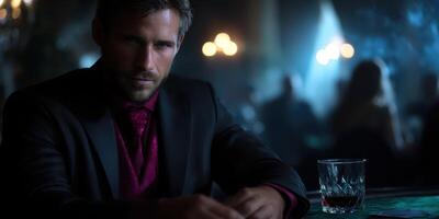 Man in a suit sitting at a dimly lit table, evening atmosphere with whiskey glass and blurred background photo