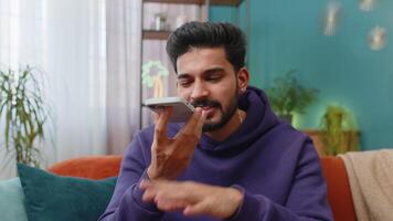 Happy Indian man making phone conversation talking with friend sitting call on couch at home video