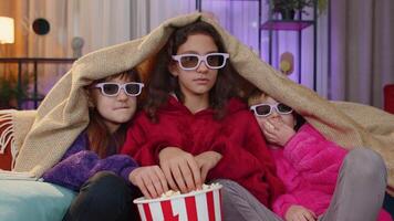 Children sits on couch eating popcorn and watching interesting TV serial sport game online at home video