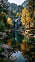 Beautiful waterfall cascading into a serene pool surrounded by autumn foliage in a mountainous forest photo