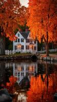 Beautiful autumn reflections of a white house surrounded by vibrant orange leaves near a calm lake at sunset photo