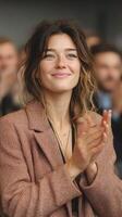 Smiling woman applauding enthusiastically during a public event in a large indoor venue photo
