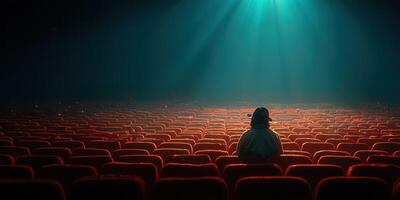 Person sitting alone in empty cinema hall during quiet evening screening photo