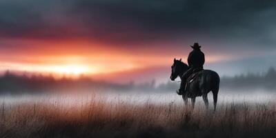Cowboy on horseback watching the sunset over a misty field during a serene evening photo
