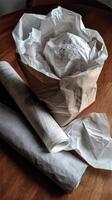 Wrapping materials and a carefully packaged item on a wooden table in a cozy indoor setting photo
