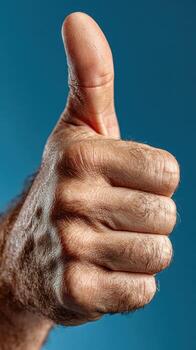 Hand giving a thumbs up gesture against a blue background representing approval and positivity photo