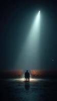 Lonely figure seated in an empty theater illuminated by a single spotlight during a misty evening performance photo