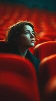 Woman gazes thoughtfully in a theater filled with red seats during a quiet moment of reflection photo