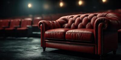 Elegant red leather couch in a dimly lit theater setting with empty seats in the background photo