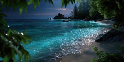 Serene beach at twilight with gentle waves lapping against rocks and vibrant blue water reflecting moonlight photo