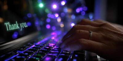 Hands typing on a laptop keyboard surrounded by colorful lights with a message saying thank you in a cozy setting at night photo