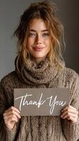 Woman in cozy sweater expressing gratitude with a thank you sign indoors photo