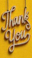 Handcrafted sign saying thank you hangs against a bright yellow wall in an inviting atmosphere photo