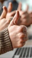 Group of people giving thumbs up in an office setting during a team meeting to celebrate achievements photo