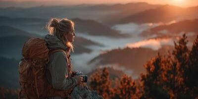 Hiker enjoys sunrise over misty mountains while capturing the beauty with a camera photo