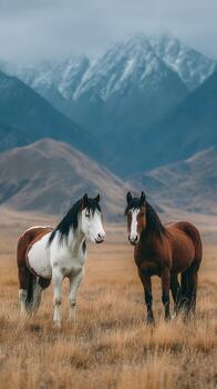 majestuoso caballos en un sereno prado con nevadas montañas durante un nublado tarde foto