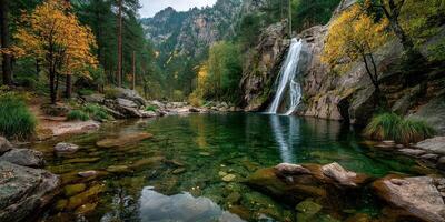 Waterfall cascading into serene pool surrounded by autumn foliage in a mountainous landscape photo