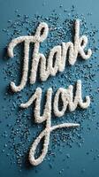 Creative thank you message crafted from sugar and sprinkles on a blue background photo