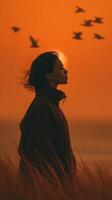 Woman enjoys a sunset by the beach with birds flying in the sky during golden hour near the ocean photo