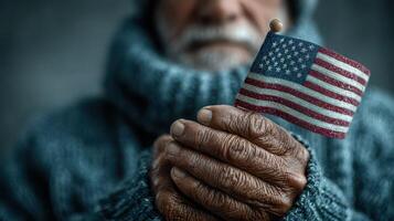Elderly man holding a small American flag in his hands, showcasing pride and patriotism in a cozy setting photo