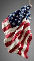 Old American flag hanging on a rope, showcasing wear and fading in a studio setting with gray background photo