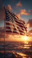 American flag waving against a sunset backdrop over the ocean, symbolizing patriotism and freedom photo