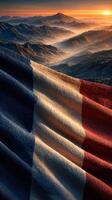 Beautiful French flag waving above majestic mountains during a breathtaking sunset photo