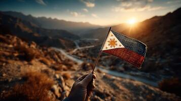 Hand holding a worn Philippine flag against a stunning mountain sunset in a remote location photo